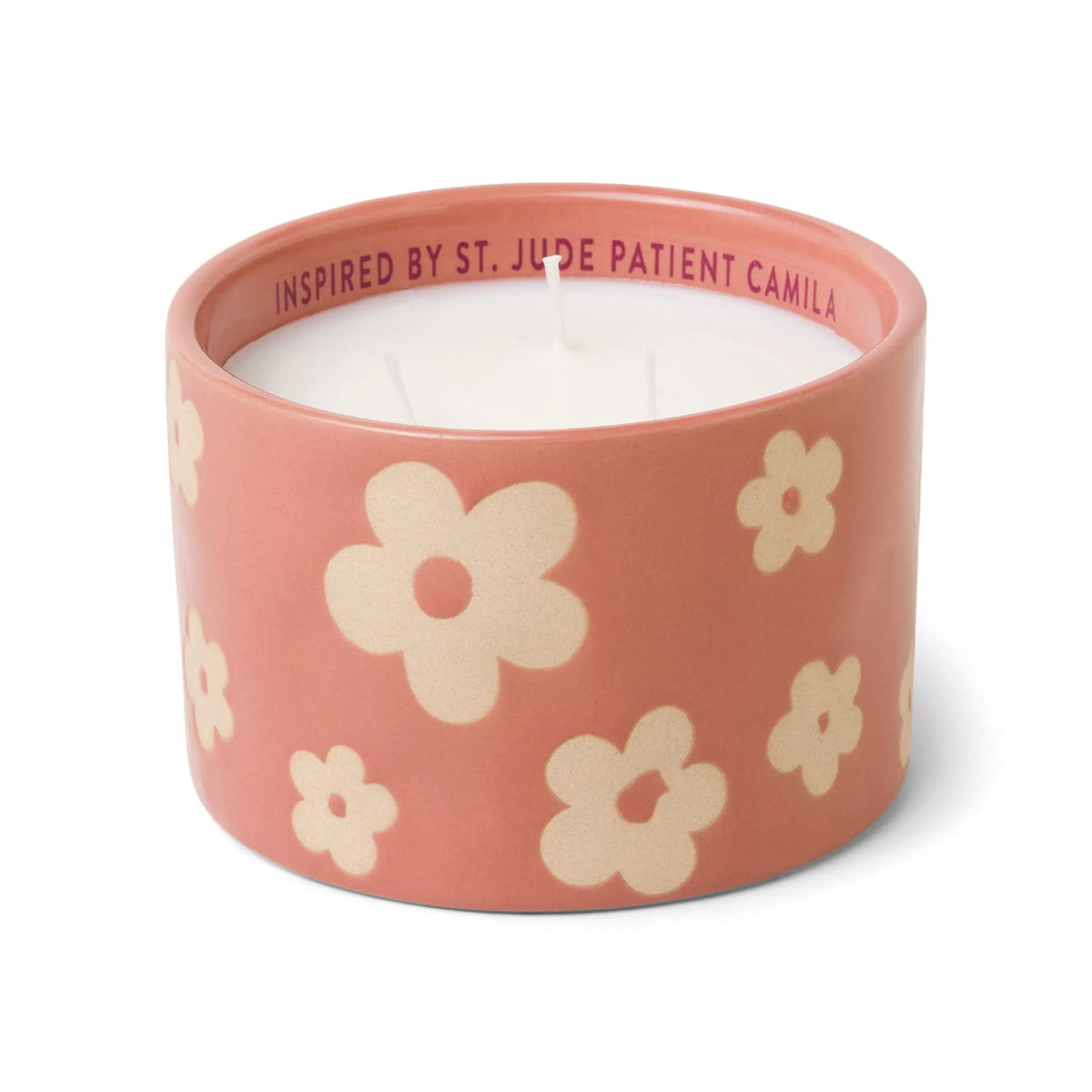 A pink ceramic candle holder adorned with cream-colored flowers and featuring two wicks, the Sky + Rain - St. Jude Giveback "Hope" 11 oz. Candle beautifully blends style and meaning. The words “INSPIRED BY ST. JUDE PATIENT CAMILA” are printed inside the rim, making it a truly heartfelt addition to any ceramic candle collection.