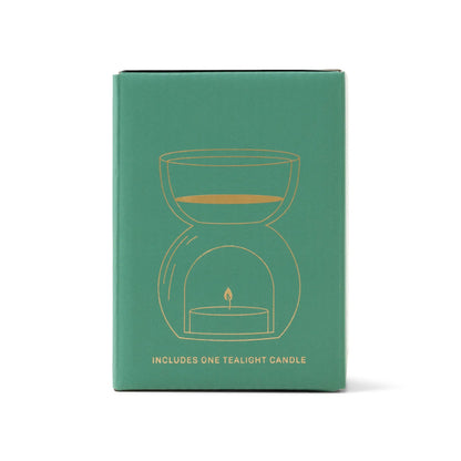 The Sage Green Glass - Essential Oil Burner & Tea Light Candle features a gold line art of an oil burner above a tealight on the box, plus text that says “Includes one tealight candle.”.
