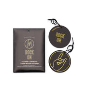 A set of two round black "Rock On" air fresheners with a hand sign, next to packaging labeled Leather + Oakmoss "Rock On" - Impressions Car Fragrance by Paddywax—perfect for bold, lasting car scents.