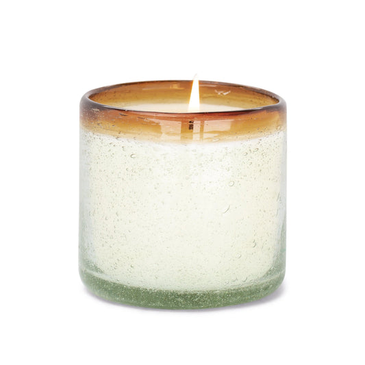 Illuminate your space with the Orange Blossom - La Playa 9 oz Candle, presented in a transparent, hand-blown bubble glass holder featuring a brown-tinted rim. Crafted from recycled glass for both elegance and sustainability, this decorative candle offers an inviting glow and an eco-friendly touch to your décor.