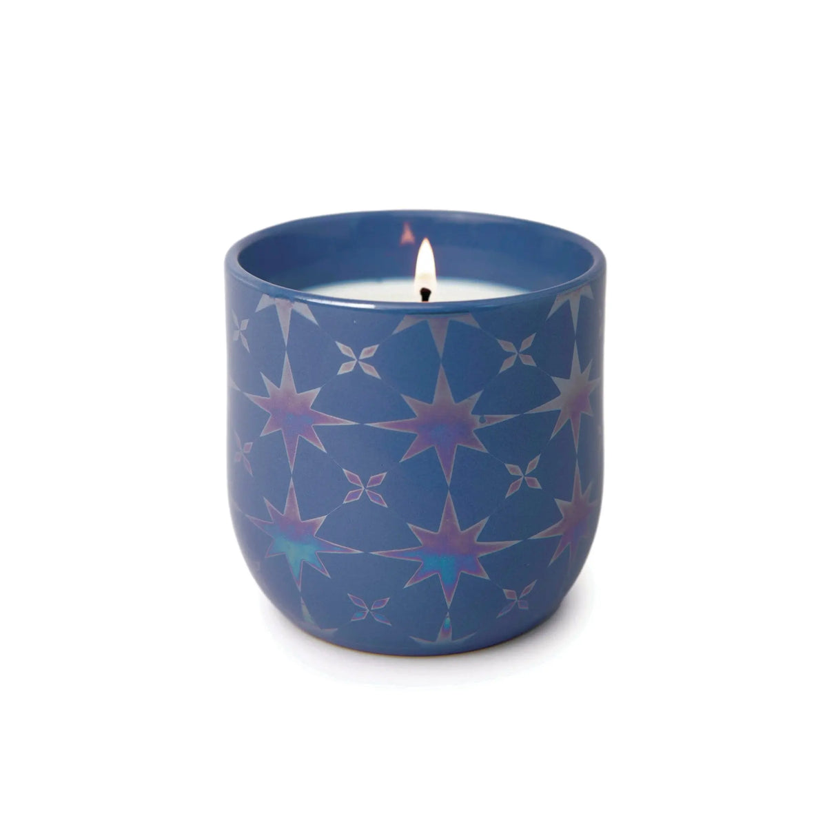 A lit Sapphire Waters - Lustre Candle 10 oz in a blue holder with iridescent star patterns, set against a plain white background.
