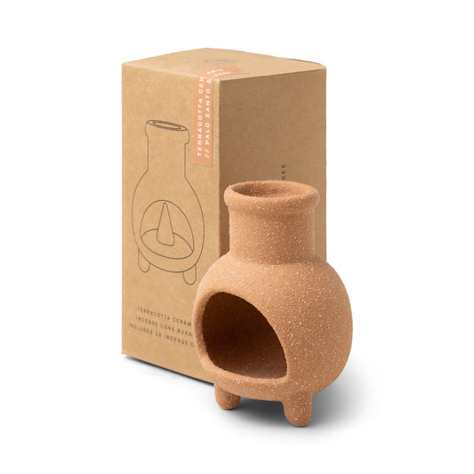 The Palo Santo & Sage - Incense Holder is a small ceramic piece shaped like a chiminea, shown beside its brown packaging with an outline drawing. Ideal for burning Palo Santo and Sage incense cones.