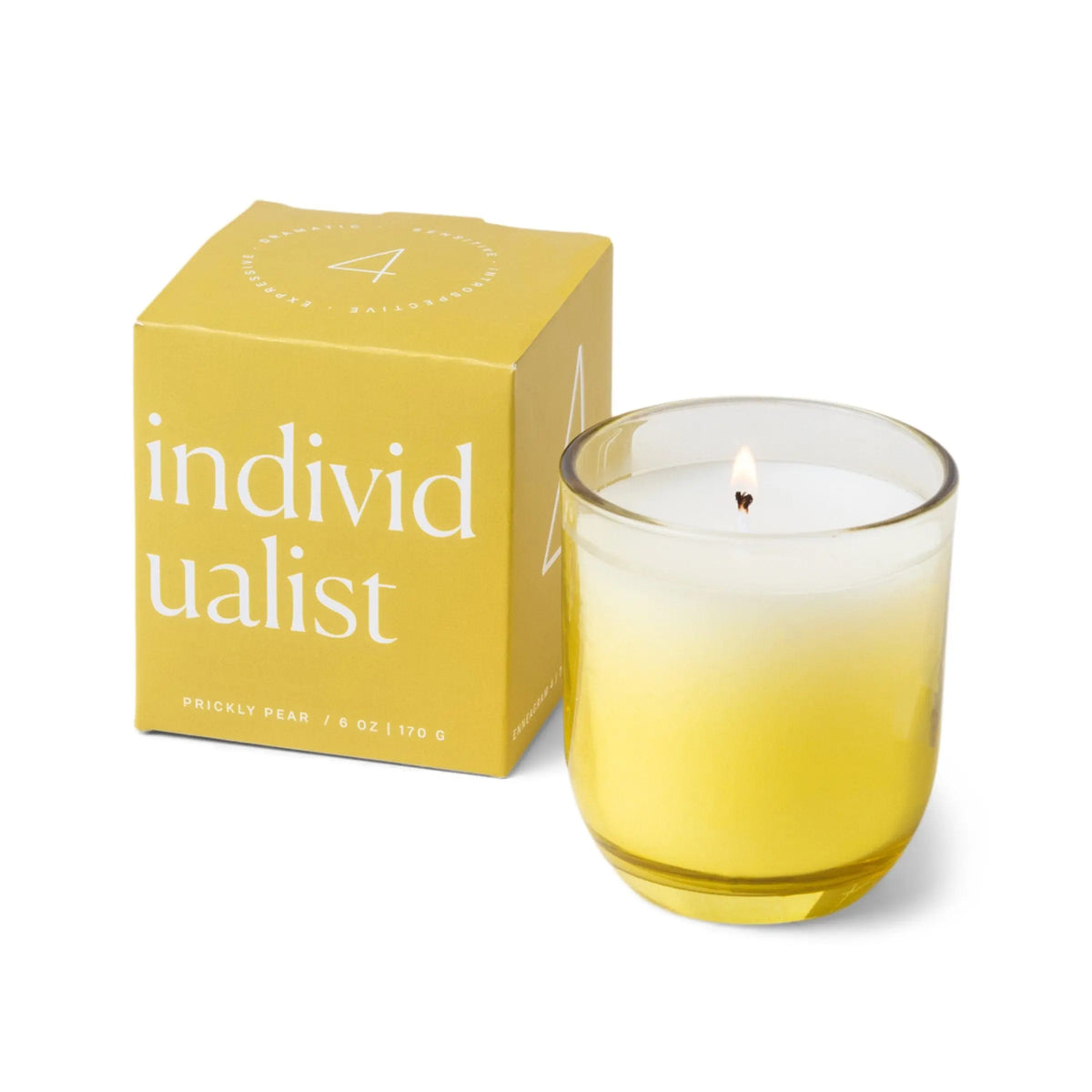 A yellow box labeled “Individualist” sits next to a glowing yellow and white candle in an ombre glass vessel. The box features the text “PRICKLY PEAR / 5 OZ,” making this Enneagram #4 Individualist Prickly Pear Candle a thoughtful addition to any fragrance gift set.